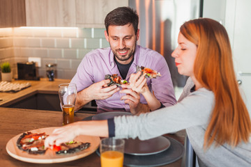 Young couple eating pizza at home