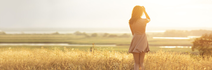 dreamy girl in a field at sunset, a young woman in a haze from the sun enjoying nature, romantic style