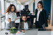 © JJ Studio - Beautiful business people are using computer and smiling while working in office