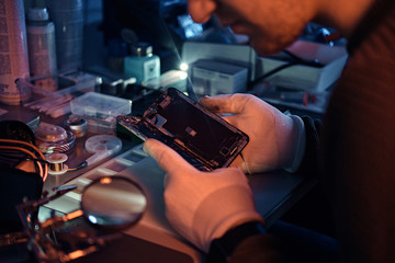 Wall Mural - The technician carefully examines the integrity of the internal elements of the smartphone in a modern repair shop