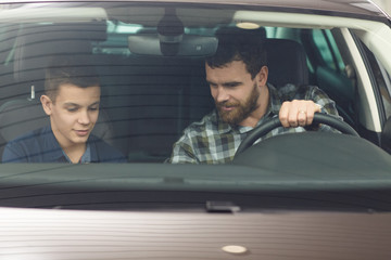 Wall Mural - Handsome mature man and his young son buying a new automobile together