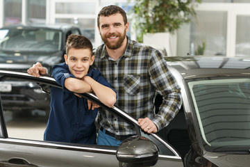 Wall Mural - Handsome mature man and his young son buying a new automobile together