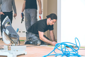 Man with a chop saw cuts skirting boards on a construction site. Lay parquet floor