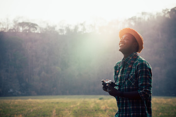 African man traveller holding film camera on a green meadow