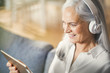 © Westend61 - senior woman using digital tablet and headphones