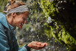 © Westend61 - Chile, Patagonia, Osorno Volcano, woman refreshing with water from Las Cascadas waterfall