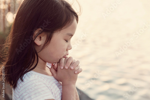 Fotografía Multicultural little girl praying with sunflare background