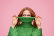 Playful girl covering face with sweater roll neck