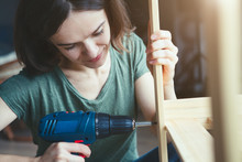 Pretty Young Woman Holding Screwdriver And Repairing Or Making Wooden Furniture
