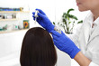 Zabieg przeciwłupieżowy. Pielęgnacja włosów. Dermatolog nakłada preparat leczniczy na skórę głowy kobiety.