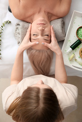 Mature woman receiving face massage in beauty salon