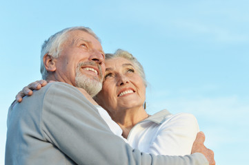 Portrait of happy senior couple hugging against blue sky