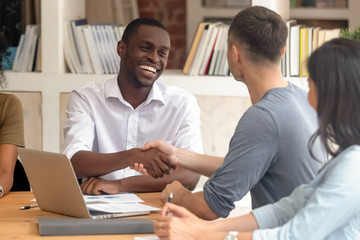 Wall Mural - happy african businessman handshaking partner at office group meeting
