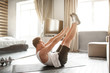 © estradaanton - Young well-built man go in for sports in apartment. He lying on back and reach feet with hands. Young man stretching. Yoga exercise.