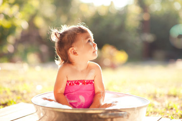 Cute baby girl 2-3 year old bathing outdoors. Looking away. Childhood.