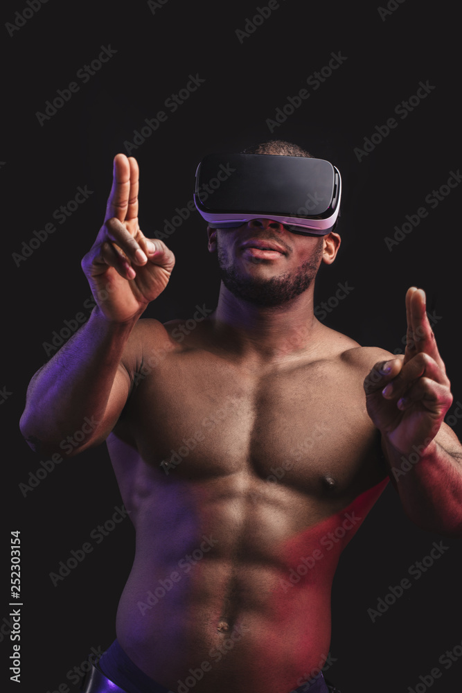 Muscular African sportsman playing 3d video game, using VR goggles ...