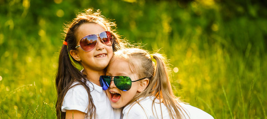 Outdoor portrait of two embracing cute little girls