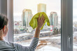 woman maid washes a window with a green sponge