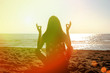 Woman meditating on the beach, close-up, rear view, back silhouette