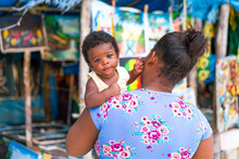 Back View Of African American Mother Holding Little Kid Near Small Souvenir Shop In Jamaica