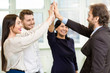 © Nestor - Successful diverse business team high fiving at the office