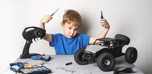 Radio Controlled Models: A Little Boy In A Blue T-shirt Is Repairing His RC Car Buggy.