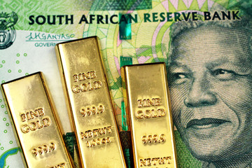a macro image of a green ten rand note from south africa with three small gold bars