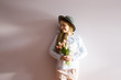 © AnastazjaSoroka - A young beautiful girl with blond dissolved long hair, a felt hat on her head, keeps spring flowers in her hands on a sunny day. Women's Day.