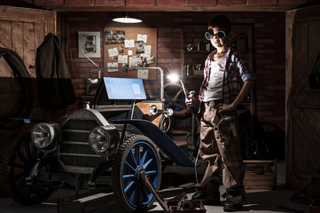 Young mechanic with a welder at the car in the garage