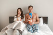 © estradaanton - Young couple in the bed. An intrigued beautiful man and woman are eating popcorn and watching TV together in bedroom