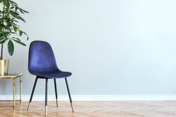 Luxury and minimalistic grey home interior with purple velvet chair, table with plant. Copy space for inscription, mock up poster. Empty wall. Brown wooden parquet.