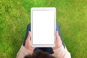 Tablet mockup with green grass, meadow in background. Woman hold white tablet with isolated screen in vertical position. White, blank screen for app or web site promotion.