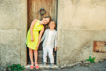 Wall Mural - Fashion portrait of adorable little boy and girl posing outdoors