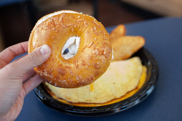 hand holding bagel with cream cheese