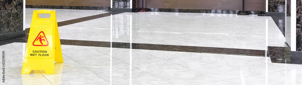 Marble shiny floor in luxury hallway of company or hotel during cleaning. Panorama of washed cleaned floor with sign of caution wet floor. Professional care service of the office interior. - obrazy, fototapety, plakaty 