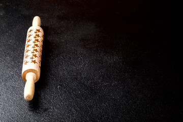 Rolling pin with a pattern in the form of stars on a black board. Baking Background .Preparation for cooking Food. Concept for Menu, Recipe, Ingredient. Copy space for Text.