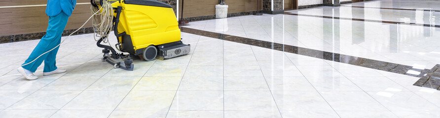 Floor care with washing machine in office lobby. Panorama of cleaning service with vacuum equipment on shiny marble floor in the luxury interior of company. Concept of professional cleaning job.