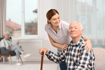 Canvas Print - Elderly man with female caregiver at home. Space for text