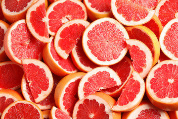 Many sliced fresh grapefruits as background, top view