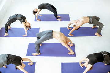 Group of athletic people keeping yoga pose during the training in the white studio