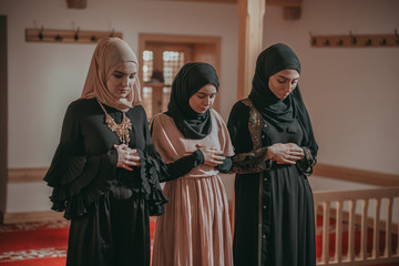 Three muslim girls pray together in mosque