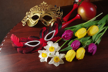 Canvas Print - A bouquet of daffodils and tulips, carnival masks on a wooden table