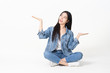 © anon - Thinking asian woman sitting on floor isolated on white background.Asian female model smiling looking up.woman pointing fingers away while sitting on a floor with legs crossed isolated