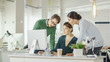 © Gorodenkoff - Young  Man and Two Women Stand before Computer Desk in a Creative Office. They Discuss Business Issues. Diverse People Working in Background.