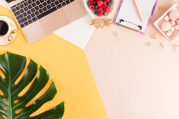 Female home office workplace with laptop, stationery on colorful pink and yellow pastel background. Flat lay of women's office desk. Top view feminine summer bright background.