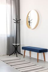 Wall Mural - Coat hanger, blue settee and round mirror in wooden frame in spacious hall