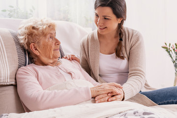 Wall Mural - Young daughter supporting sick mother lying in hospital bed