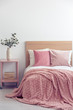 © Photographee.eu - Pink pillows and cozy blanket on single bed in elegant hotel room, copy space on empty white wall
