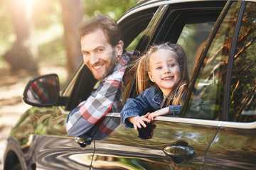 Time is precious. Waste it wisely. Father and daughter looking out the car window and smiling happily at the camera. Family road trip