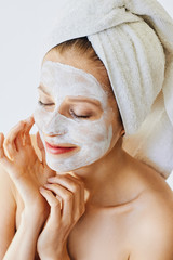 Wall Mural - beautiful young woman with facial mask on her face. skin care and treatment, spa, natural beauty and